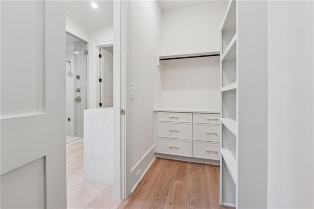 walk in closet with light wood-style flooring