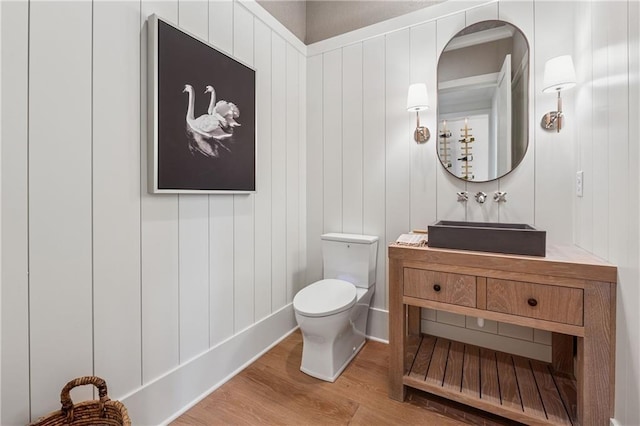 half bathroom featuring toilet, wood finished floors, and vanity
