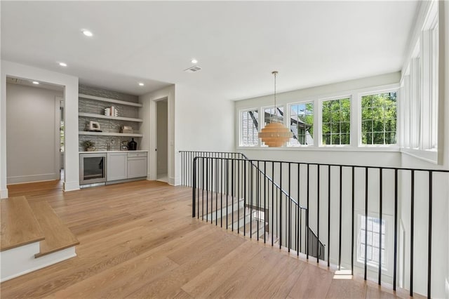 corridor featuring light wood-type flooring, recessed lighting, an upstairs landing, visible vents, and wine cooler