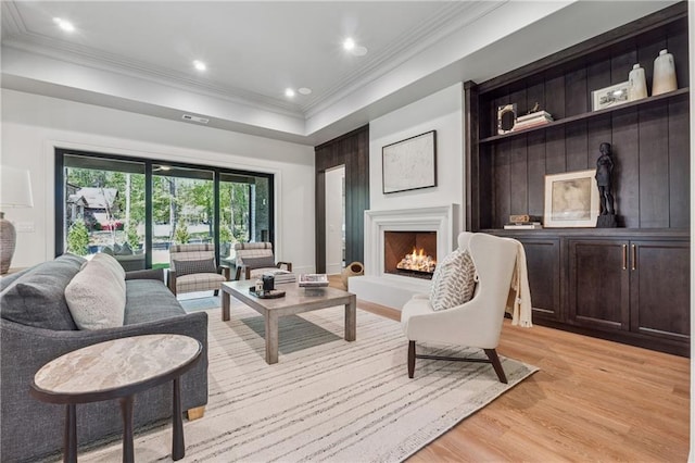 living room with ornamental molding, visible vents, a warm lit fireplace, recessed lighting, and light wood finished floors