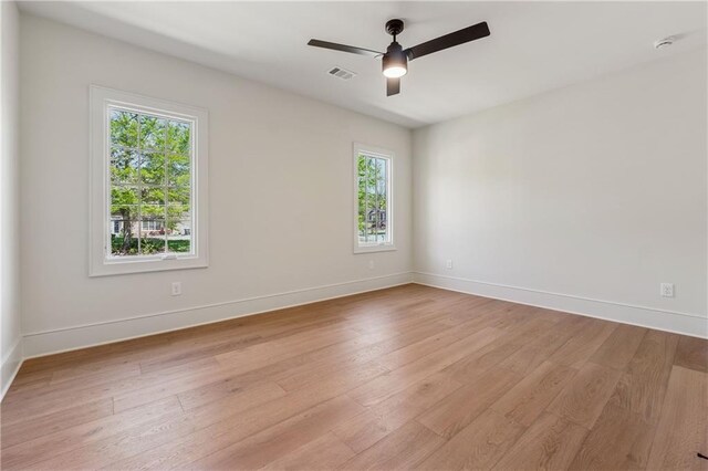 spare room with light wood-style flooring, baseboards, visible vents, and a ceiling fan