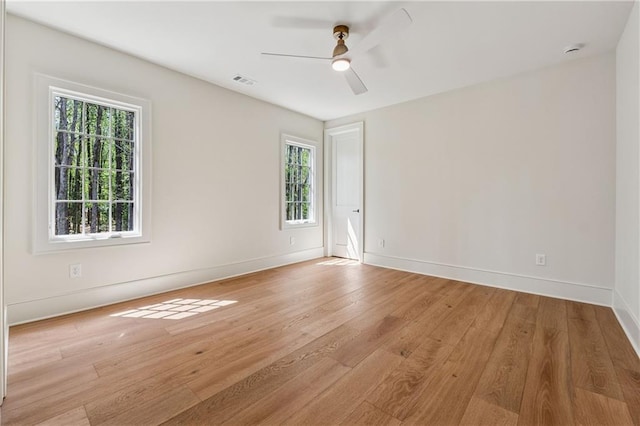 spare room featuring light wood finished floors, visible vents, baseboards, and ceiling fan