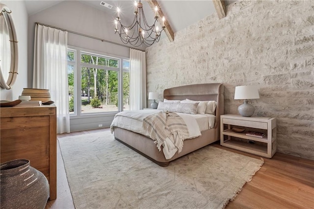 bedroom featuring visible vents, high vaulted ceiling, an inviting chandelier, and wood finished floors