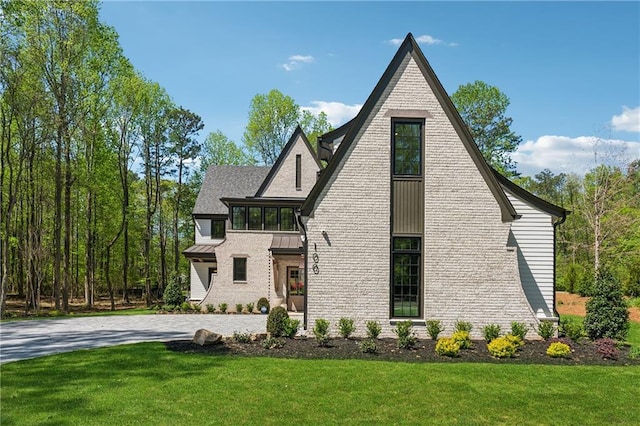 view of property exterior with a yard, roof with shingles, and driveway