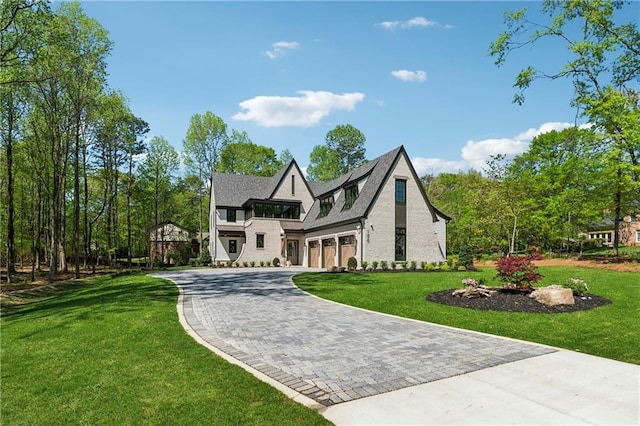 english style home with a garage, a front yard, and decorative driveway