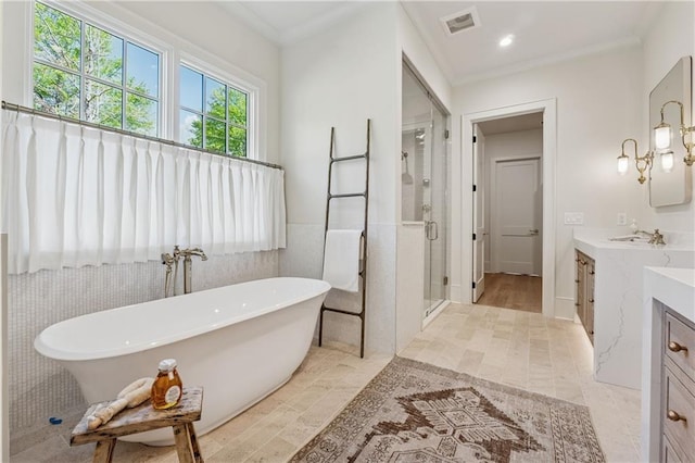 bathroom with crown molding, a soaking tub, a shower stall, vanity, and visible vents