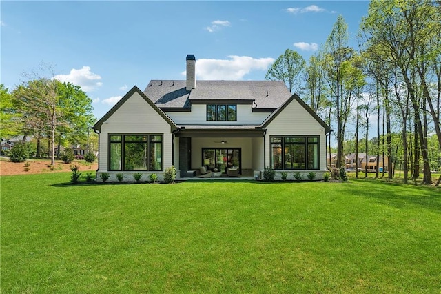 rear view of house with a chimney and a lawn