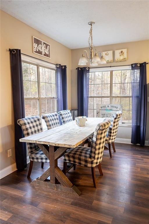 dining space featuring plenty of natural light, an inviting chandelier, and dark hardwood / wood-style flooring