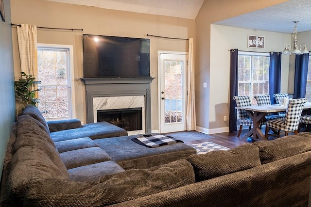 living room featuring hardwood / wood-style flooring, lofted ceiling, a high end fireplace, and a chandelier