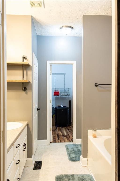 bathroom with vanity, tile patterned flooring, a washtub, and a textured ceiling