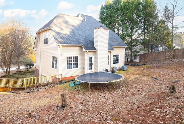 rear view of property with a trampoline and central air condition unit