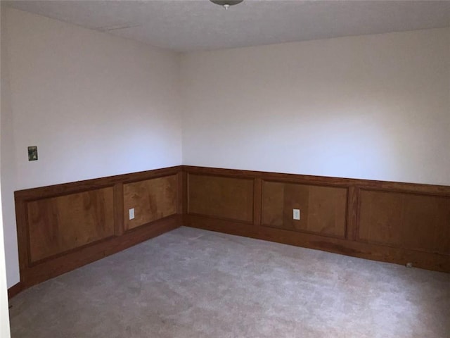 spare room with light carpet and wood walls