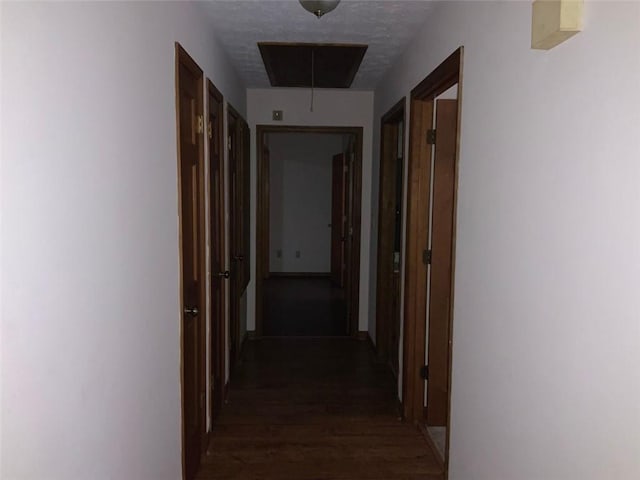 corridor featuring a textured ceiling and dark hardwood / wood-style floors