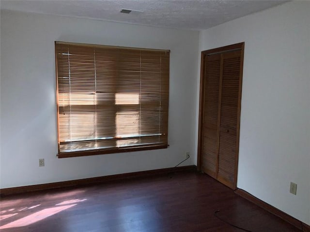 spare room featuring dark hardwood / wood-style flooring and a textured ceiling