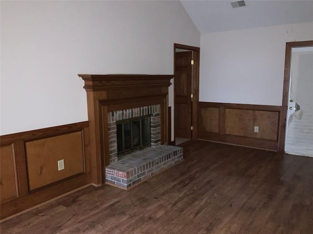 unfurnished living room featuring vaulted ceiling, wooden walls, a fireplace, and dark hardwood / wood-style floors