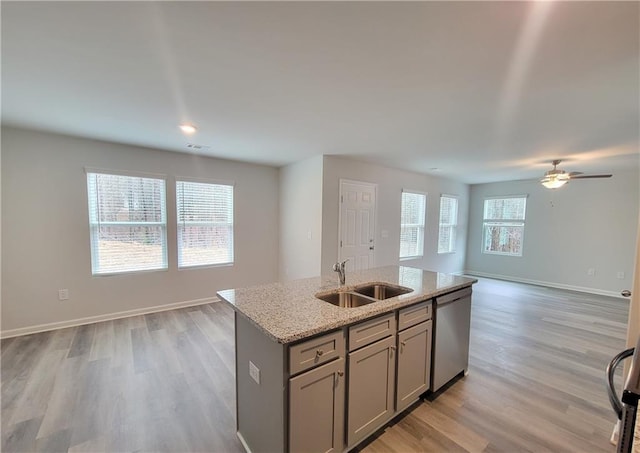 kitchen with sink, gray cabinets, dishwasher, a kitchen island with sink, and light stone counters