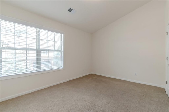 carpeted spare room with vaulted ceiling