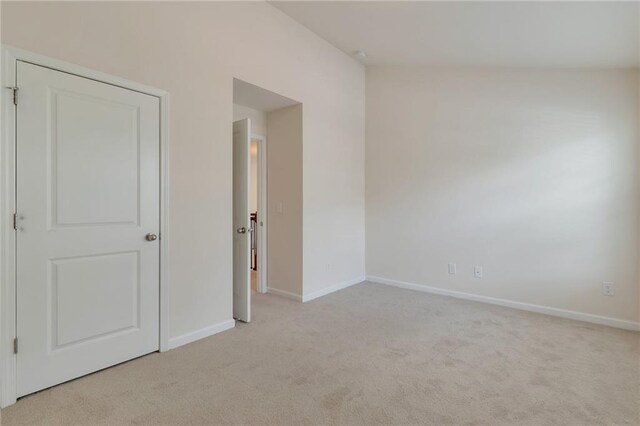 unfurnished bedroom featuring vaulted ceiling and light carpet