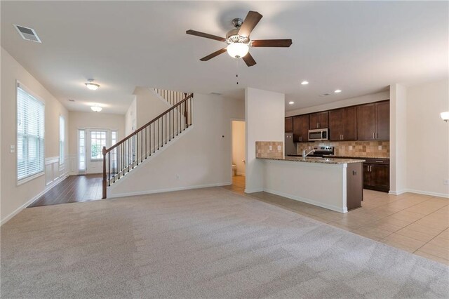 kitchen with backsplash, appliances with stainless steel finishes, light colored carpet, kitchen peninsula, and ceiling fan