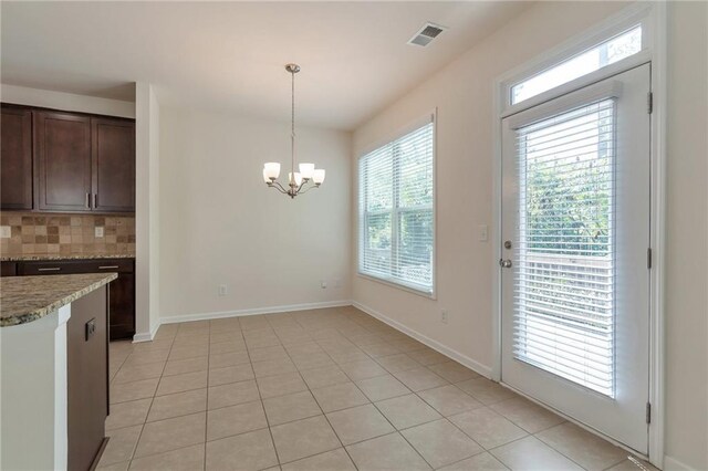 interior space with light tile patterned floors, hanging light fixtures, a notable chandelier, and decorative backsplash