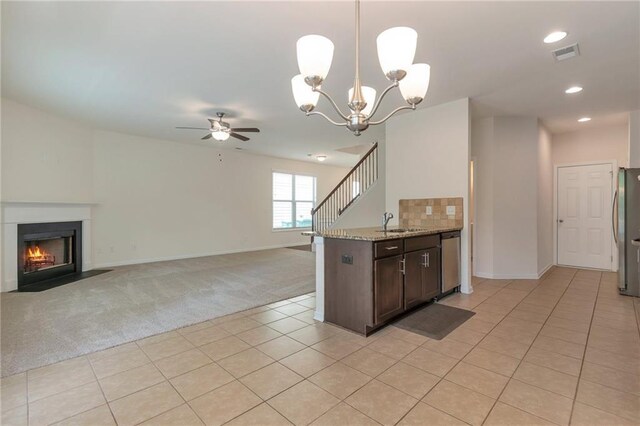 kitchen featuring light carpet, hanging light fixtures, ceiling fan with notable chandelier, sink, and stainless steel appliances