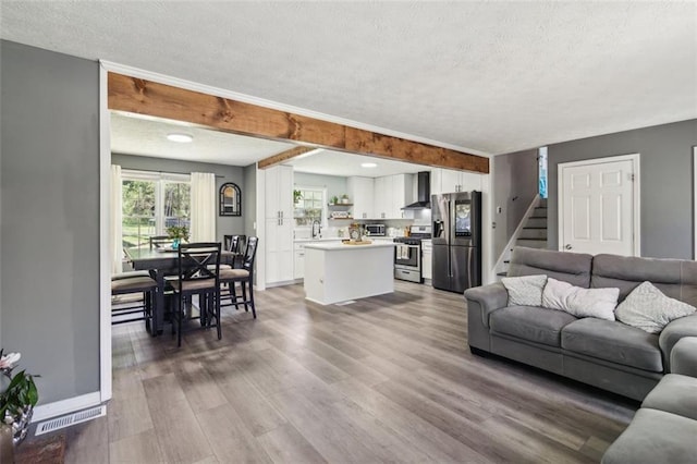 living room with stairs, wood finished floors, baseboards, and a textured ceiling