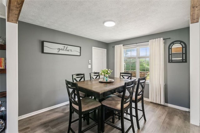 dining room featuring baseboards, dark wood-style flooring, and a textured ceiling