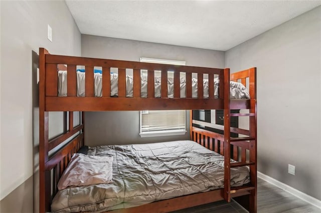 bedroom with baseboards, a textured ceiling, and wood finished floors