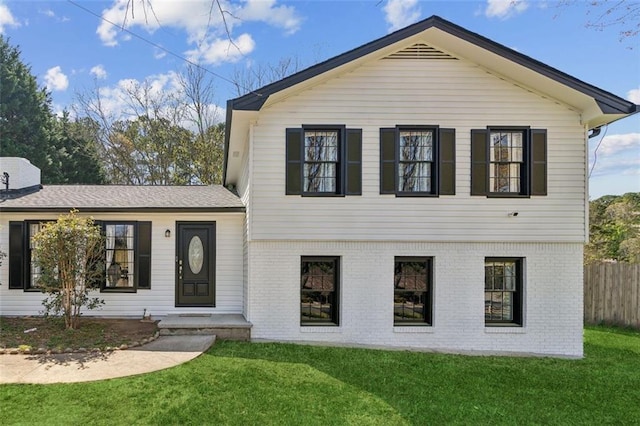 view of front of house featuring a front yard, fence, and brick siding
