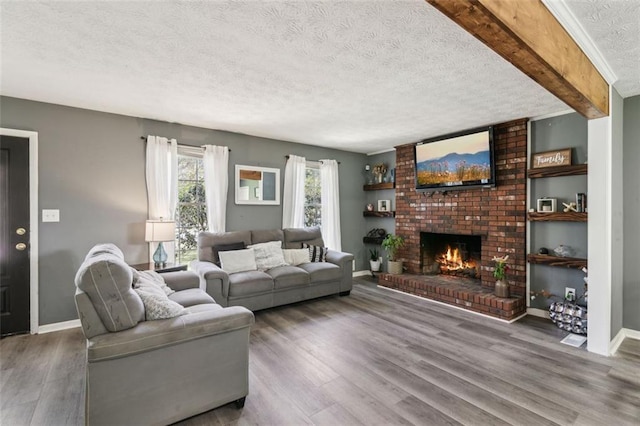 living room featuring a brick fireplace, a textured ceiling, baseboards, and wood finished floors