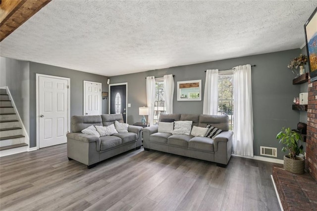living room with visible vents, baseboards, a fireplace, wood finished floors, and stairway
