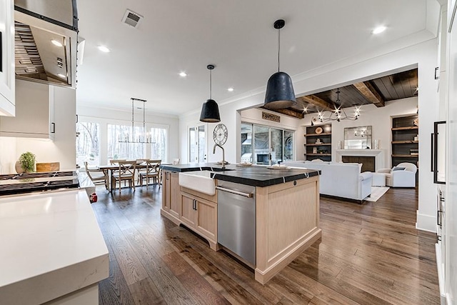 kitchen featuring light brown cabinetry, open floor plan, a sink, an island with sink, and dishwasher