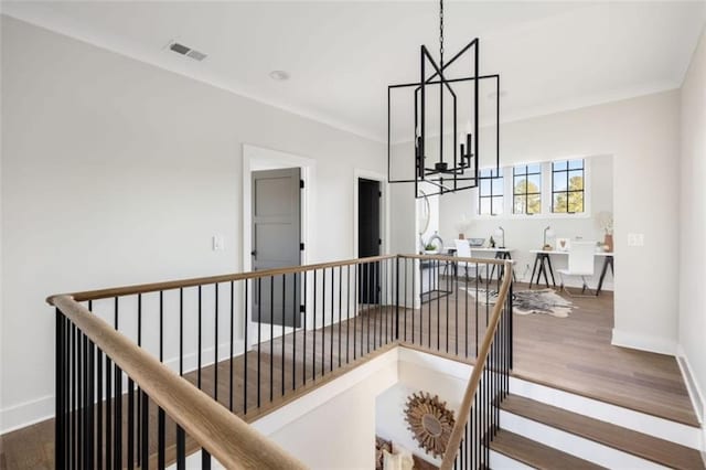 staircase featuring an inviting chandelier, baseboards, visible vents, and wood finished floors