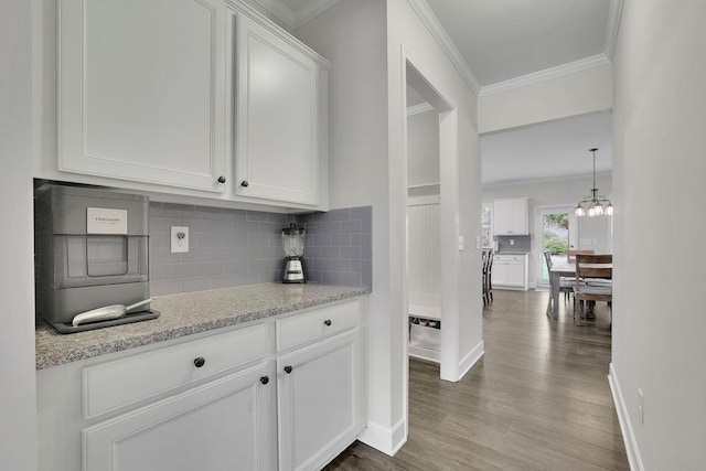 7190 Tributary Ct, Cumming, GA 30040 - kitchen with crown molding, backsplash, wood finished floors, white cabinetry, and baseboards