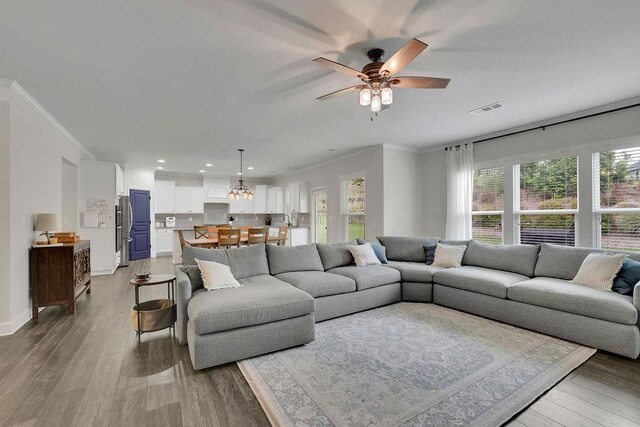 7190 Tributary Ct, Cumming, GA 30040 - living room with wood finished floors, ceiling fan, crown molding, recessed lighting, and a chandelier