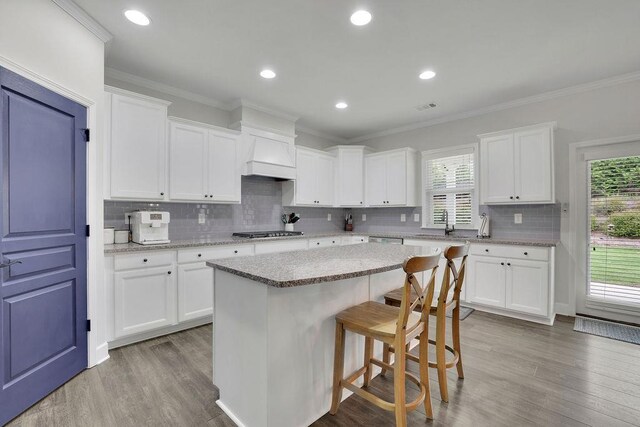 7190 Tributary Ct, Cumming, GA 30040 - kitchen featuring stainless steel appliances, wood finished floors, plenty of natural light, a center island, and ornamental molding