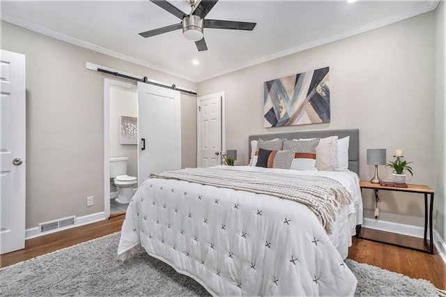 bedroom featuring ensuite bath, dark wood-type flooring, ceiling fan, crown molding, and a barn door