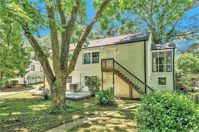 back of property with central AC unit, a patio area, and a yard