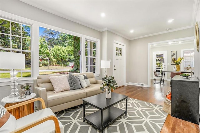 living room with a wealth of natural light, ornamental molding, and hardwood / wood-style floors