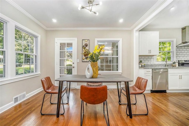 dining room featuring light hardwood / wood-style floors, ornamental molding, and an inviting chandelier