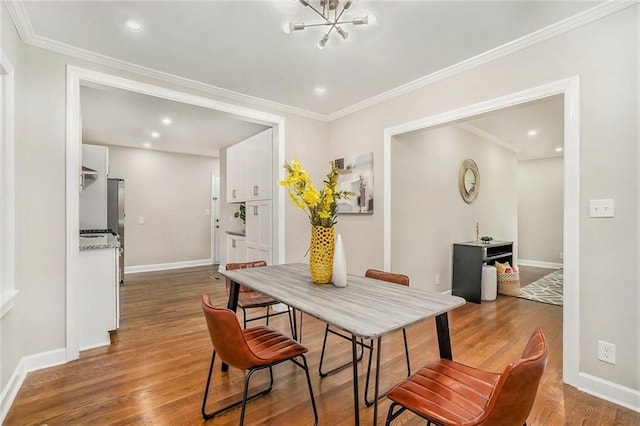 dining room with hardwood / wood-style floors, crown molding, and a chandelier