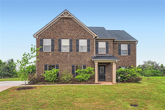 view of front facade with brick siding and a front yard