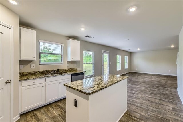 kitchen featuring visible vents, stainless steel dishwasher, a sink, dark wood-style floors, and dark stone counters