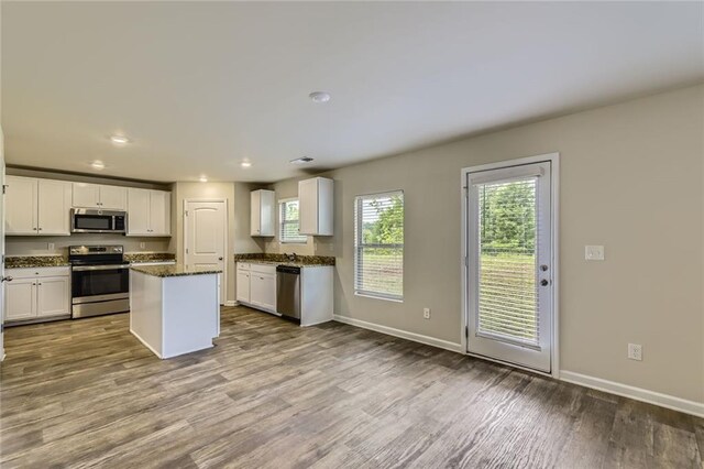 kitchen with appliances with stainless steel finishes, plenty of natural light, white cabinetry, and wood finished floors