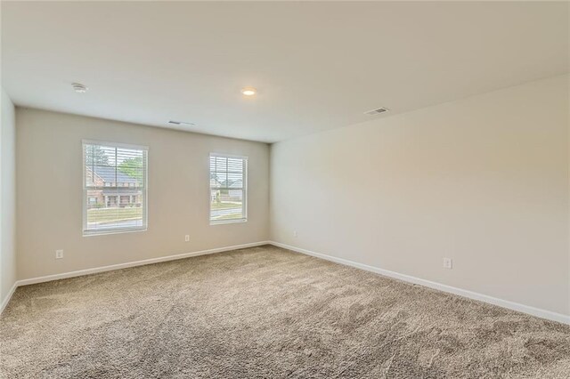 spare room with baseboards, carpet, and visible vents