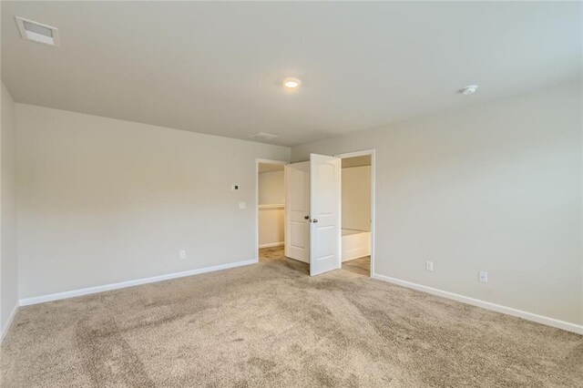 unfurnished room featuring baseboards, visible vents, and light carpet