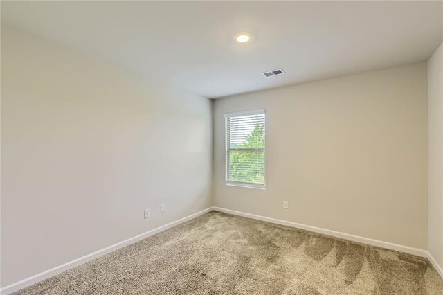 spare room with carpet flooring, baseboards, and visible vents