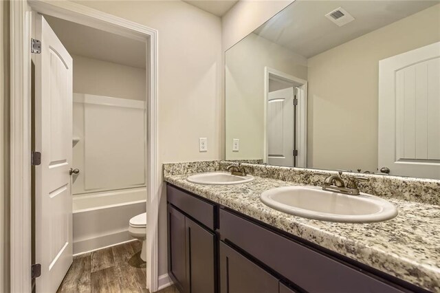 bathroom with toilet, visible vents, a sink, and wood finished floors