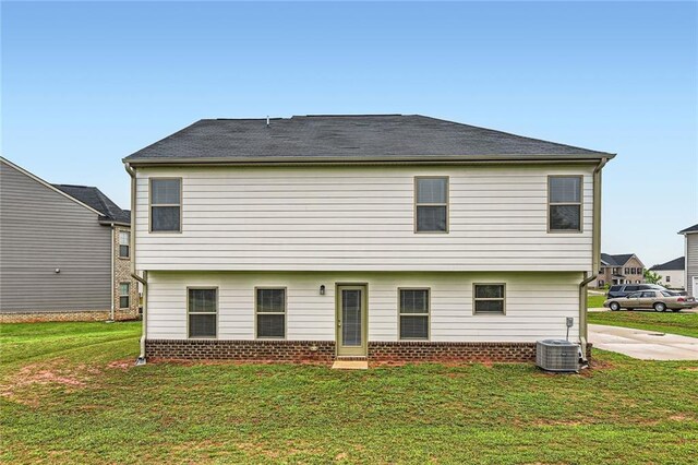 rear view of property with a lawn, brick siding, and cooling unit