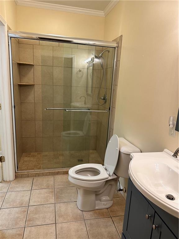 bathroom featuring tile patterned flooring, toilet, an enclosed shower, and ornamental molding